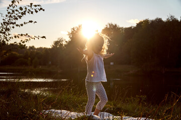 Happy child at sunset near the trees and lake. Happy childhood. The joy of kids. High quality photo