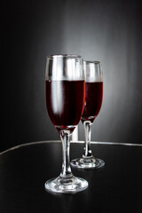 Two glasses of freshly poured red wine on black background