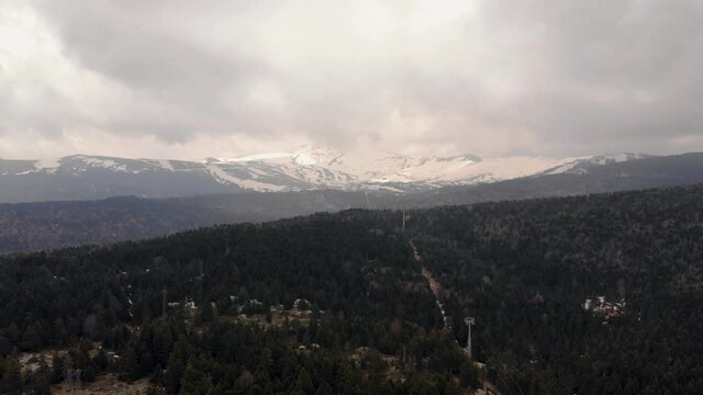 Coniferous forest in the background of snow-clad mountains of Uludag, Bolu. Aerial view 4K