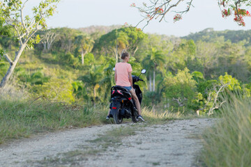 Attractive woman traveling on scooter in tropical island.
