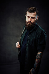 Young bearded hipster guy with backpack in dark studio