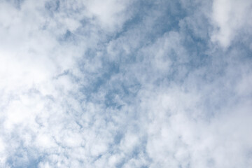 Gentle fluffy beautiful clouds on a light blue sky, located at the edges of the frame and forming a frame around the center.