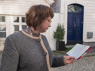 Middle aged woman lost in the old European city and looking at a map for right way