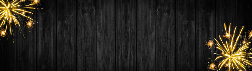 Fototapeta premium Festive silvester Party celebration background panorama banner long - Golden yellow firework on black rustic wooden wall texture with space for text
