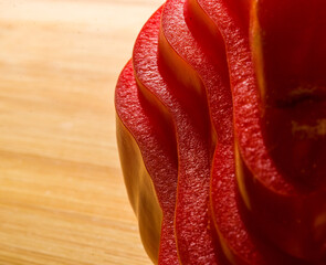 stacked pile of sliced fresh red paprika, bell pepper on bamboo cutting Board