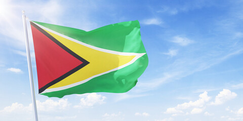 Guyana flag on a flagpole waving in blue cloudy sky. Guyana concept 3D rendering