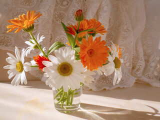 Delicate chamomile flowers and yellow calendula on a light, wooden background on a Sunny day. Rustic style. Summer