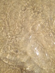 A beautiful multi-colored structure of sand, shells, pebbles, and seawater. Mediterranean beach, background, abstraction.