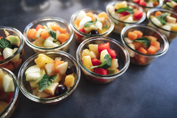 Rows of transparent glass dishes with fruit salad. Fresh fruit pieces for refreshment. Celebration, party, birthday or wedding concept.