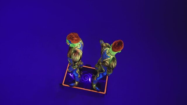 Twins acrobats in neon costumes 
perform handstands on the arms and head,
on blue cyclorama in ultraviolet make up in an alien style.
