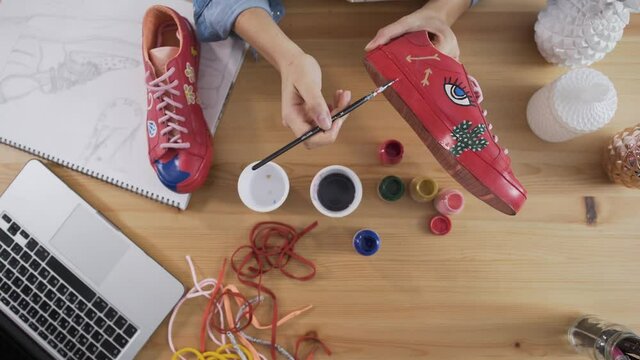 Top view of fashion designer re-purposing sneakers by painting them