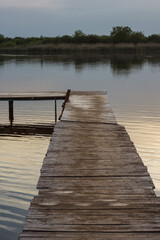 Wooden old pier on the background of the lake in which reflects the evening sky. After sunset