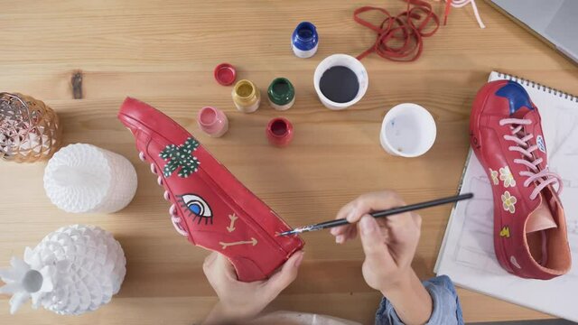 Top view of woman painting trainers for customization