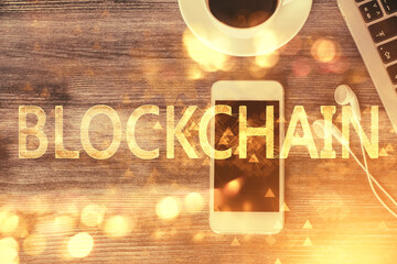 Double exposure of blockchain theme hologram over table with phone. Top view. Crypto technology...