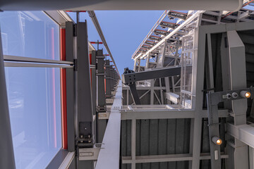 View through structural steel and glass work towards the blue sky on top of a skyscraper
