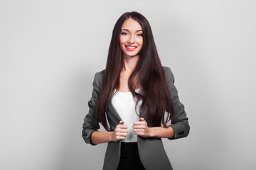 Success businesswoman with dark hair standing on a gray background