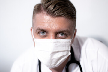 Portrait of smiling young caucasian male doctor wear white medical uniform, stethoscope and mask