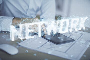 Double exposure of man's hand holding and using a digital device and data theme hologram drawing....