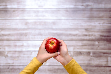 manos de mujer ofreciendo una manzana roja
