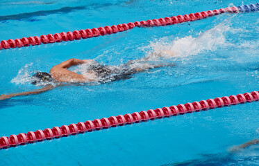 Young boy swimming Freestyle posture in the blue water pool.