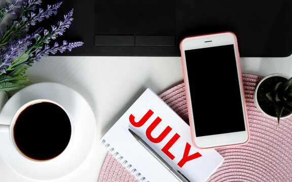 On a blue background next to a calculator, markers and a sheet of sheflera lies a notebook with the words Hello July