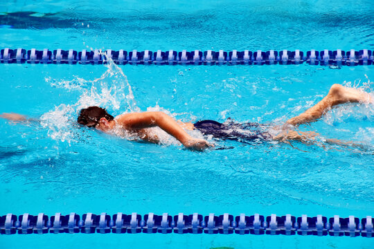 Young boy swimming Freestyle posture in the blue water pool.
