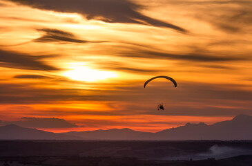 paragliding at sunset with the sun and clouds