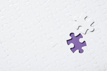 Blank white puzzle with separated piece on purple background, top view. Space for text
