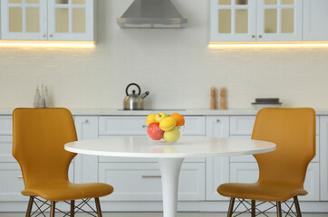 Table with orange chairs in modern kitchen interior