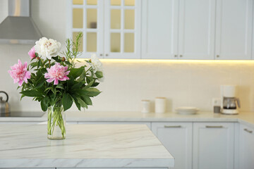 Peony bouquet on white marble table in kitchen interior