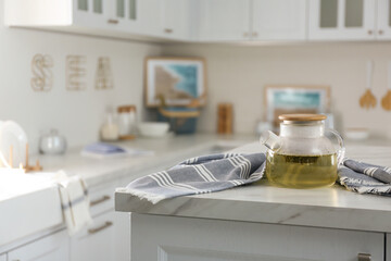 Teapot and towel on white marble table in modern kitchen. Interior design