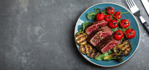 Delicious sliced beef steak served on grey table, flat lay with space for text. Banner design