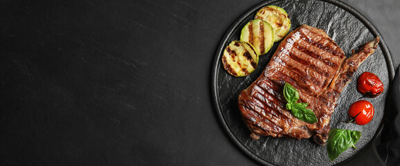 Slate plate with grilled meat steak and space for text on black table, top view. Banner design