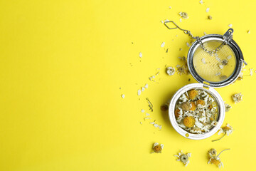 Dry chamomile flowers in infuser on yellow background, flat lay. Space for text