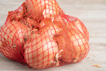 White Onions In A Flexible Red Wire Mesh Retail Packaging Bag