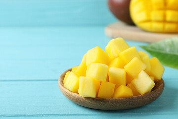 Cubes of fresh ripe mango on light blue wooden table. Space for text