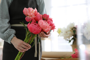 Florist with beautiful peony bouquet indoors, closeup. Space for text