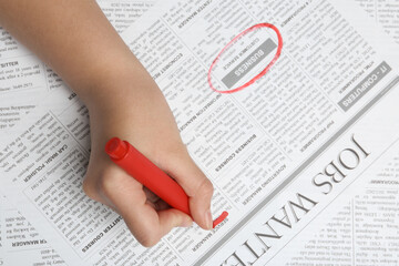 Obraz premium Woman marking advertisement in newspaper, closeup. Job search concept