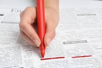 Obraz premium Woman marking advertisement in newspaper, closeup. Job search concept