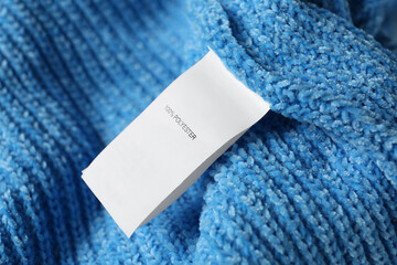 Clothing label with material content on blue sweater, closeup view