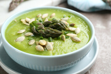 Delicious asparagus soup in bowl on grey marble table, closeup