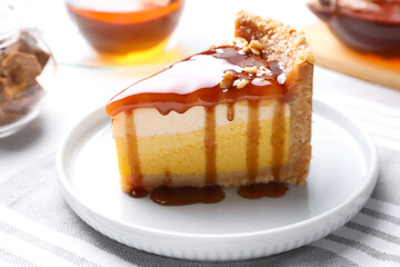 Slice of delicious cake with caramel sauce on table