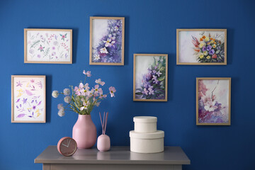 Beautiful artworks hanging on blue wall in stylish room. Interior design