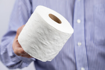 closeup of a man holding a roll of toilet paper
