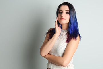 Young woman with bright dyed hair on light background, space for text