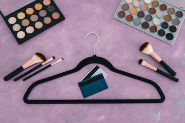 shopping concept, pink desk with cosmetics and fashion accessories on it including clothes hanger...