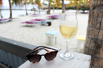 glass of champagne wine on beach with string lights tropical scene white sand