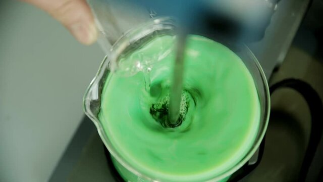 Mixing colored reagents in glass flask. Manufacture cosmetic ingredients