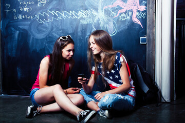 back to school after summer vacations, two teen real girls in classroom with blackboard painted together, lifestyle people concept