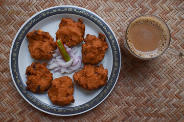 Top view of Dal vada, masala vada, chana vada served with cut onion and green chilly and Tea on...